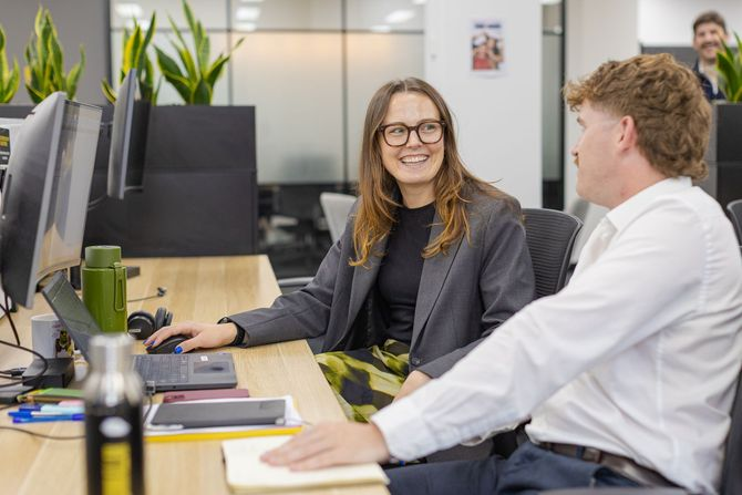 Two Quinn Allan consultants talking with a candidate at a desk